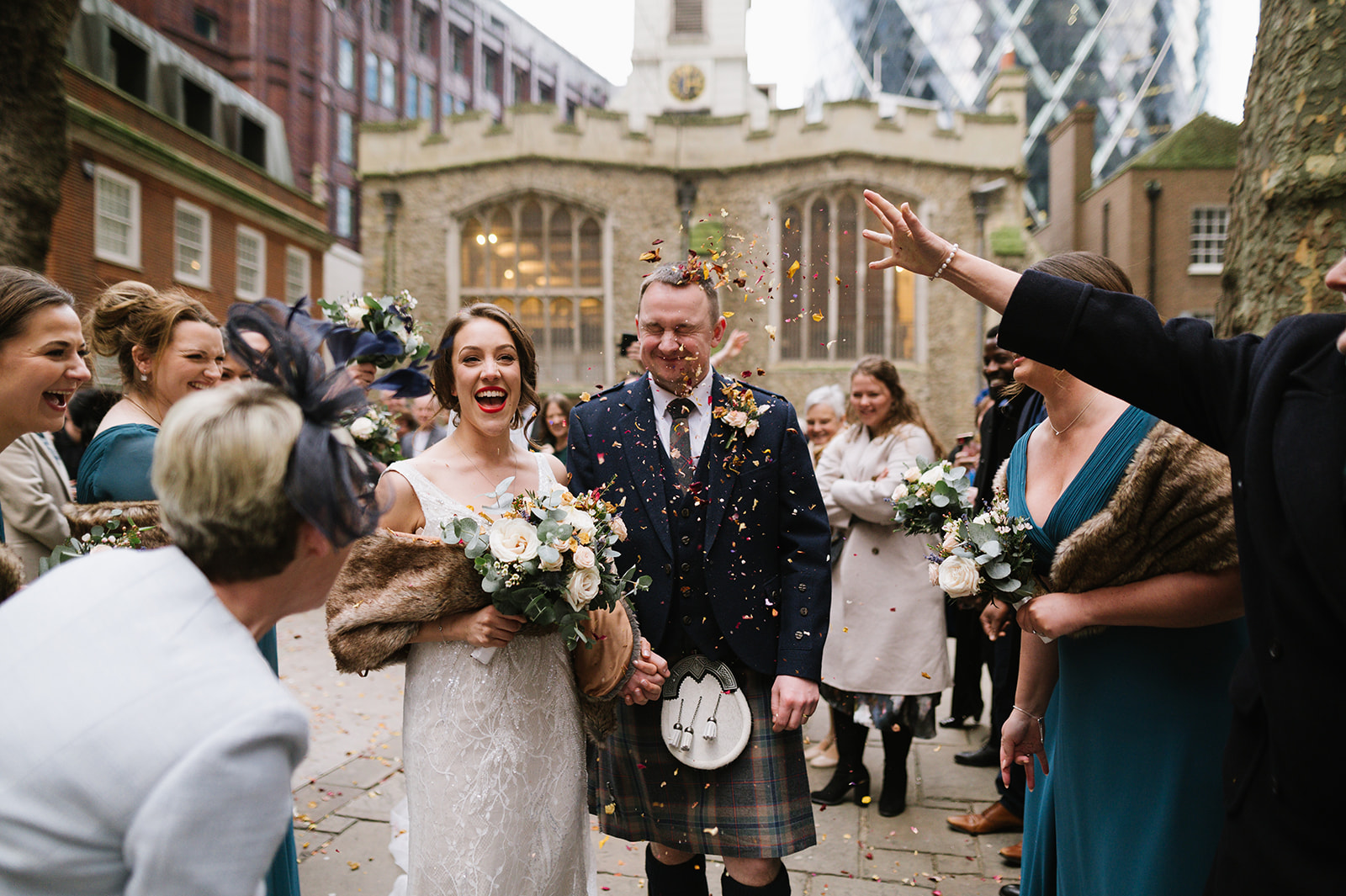 Guests throw confetti at St Helen's Church Bishopsgate after the wedding, with the gherkin in the background. 