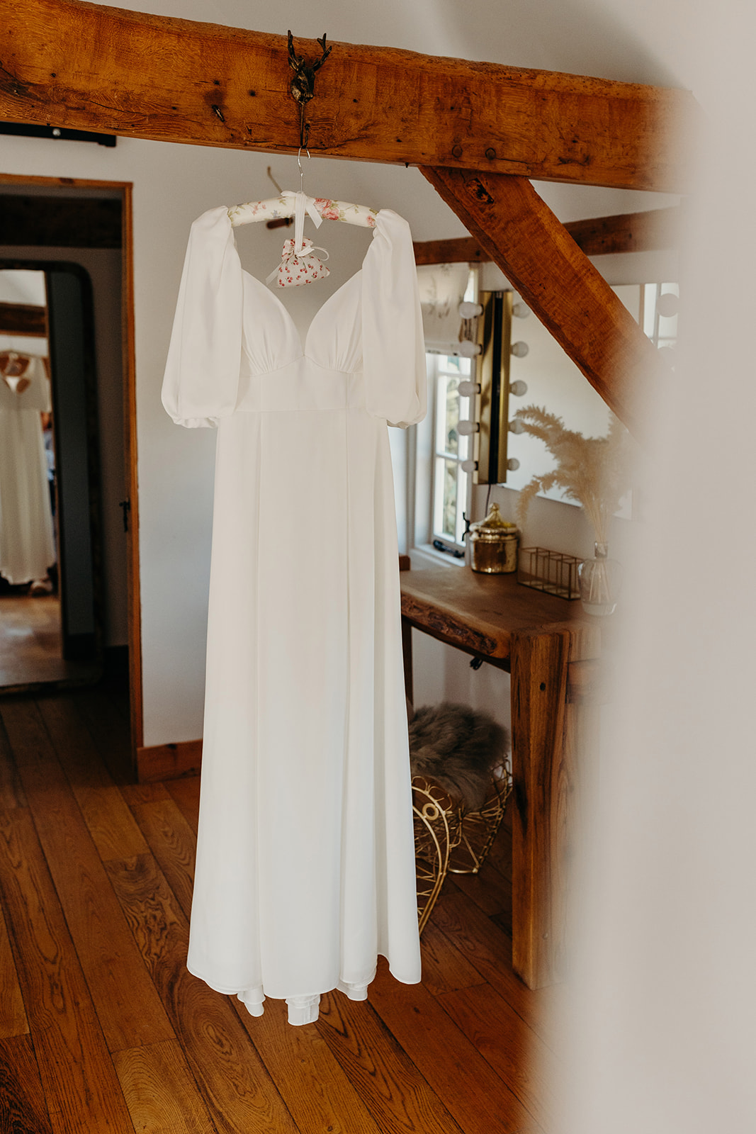 Bride's elegant wedding dress hanging in the bridal suite at Silchester Farm.
