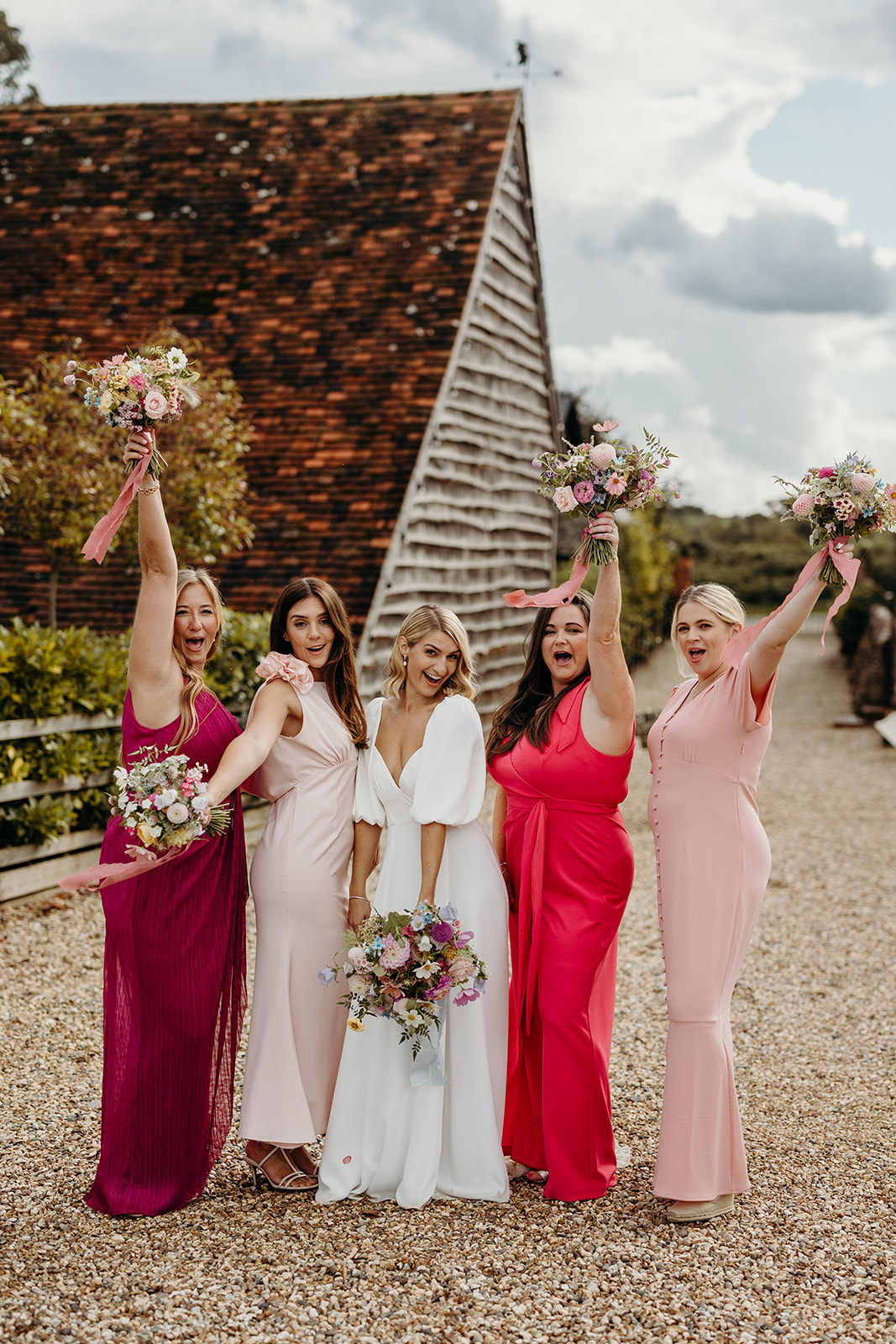 Bride with Bridesmaids posing with flowers up in the air