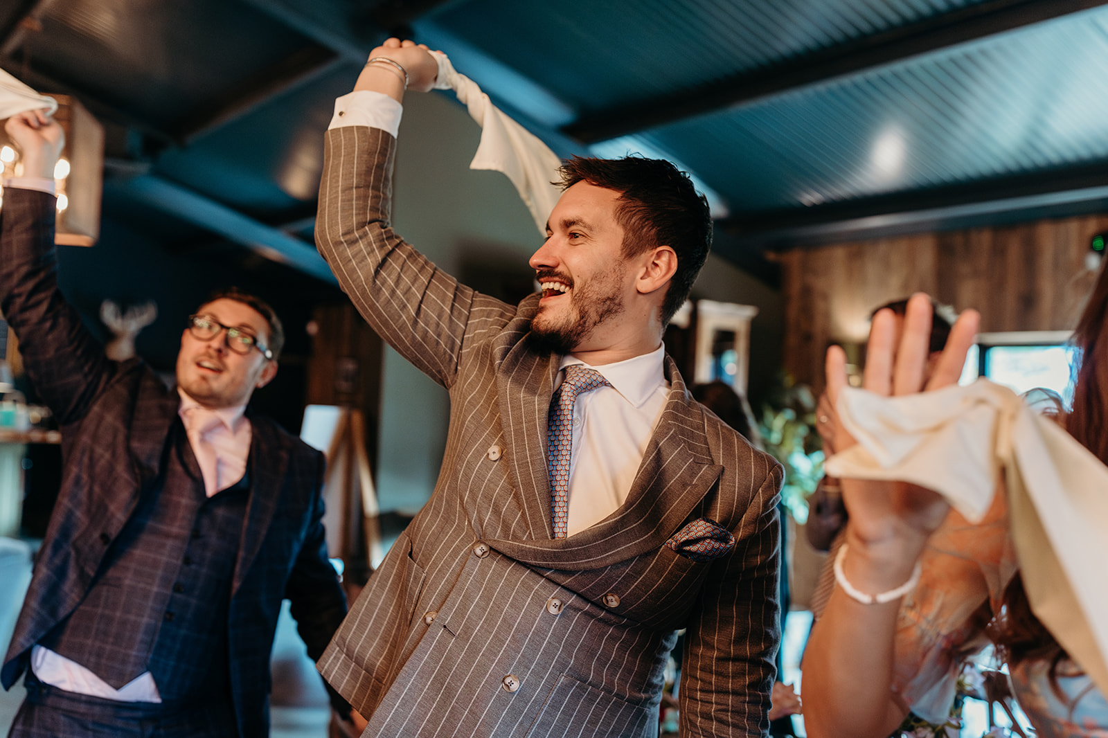 Guests cheering and waving napkins as the newlyweds dance between tables at their Silchester Farm wedding reception.