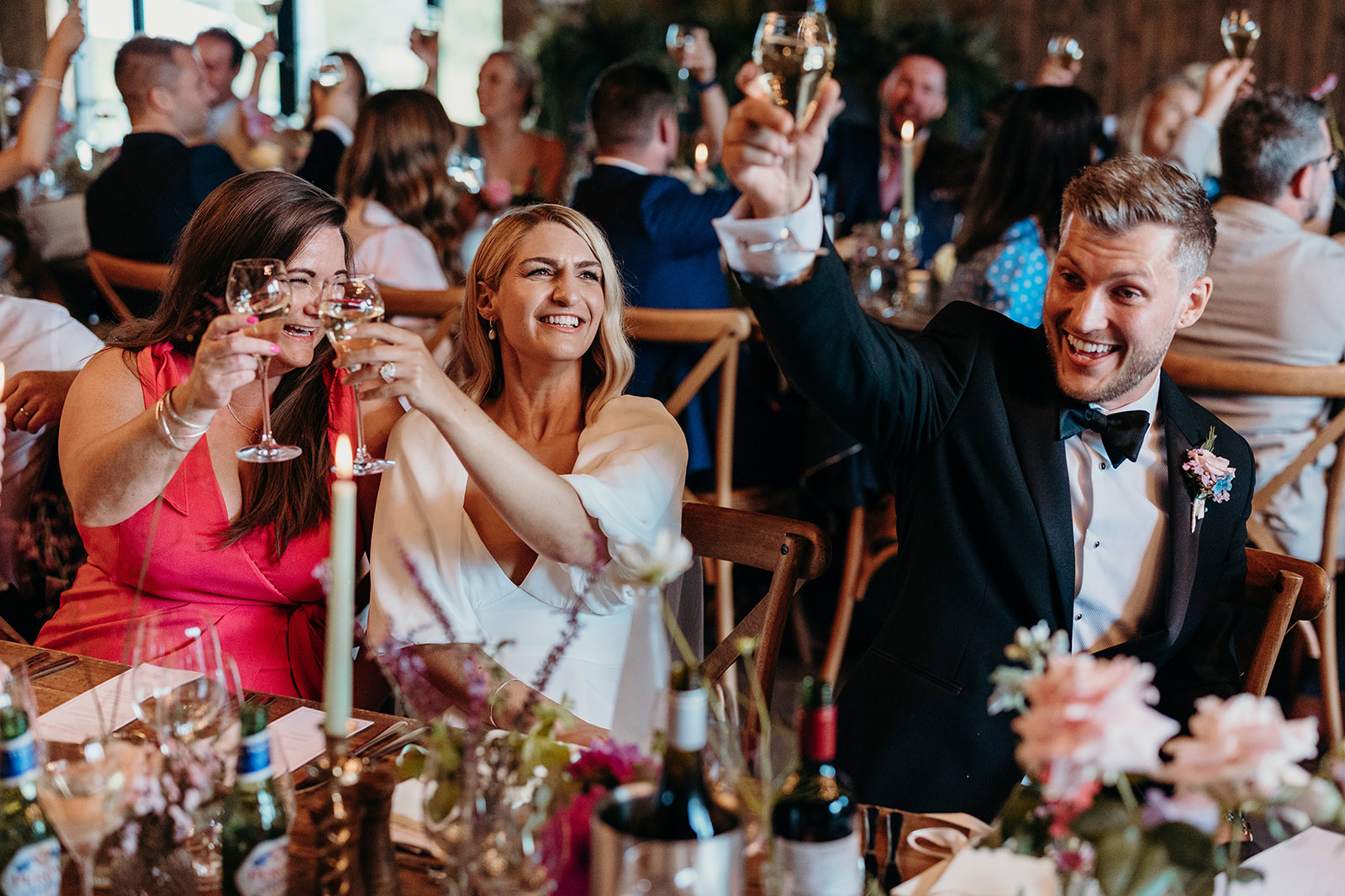 Guests raising their glasses for a toast to the happy couple at their farm wedding.
