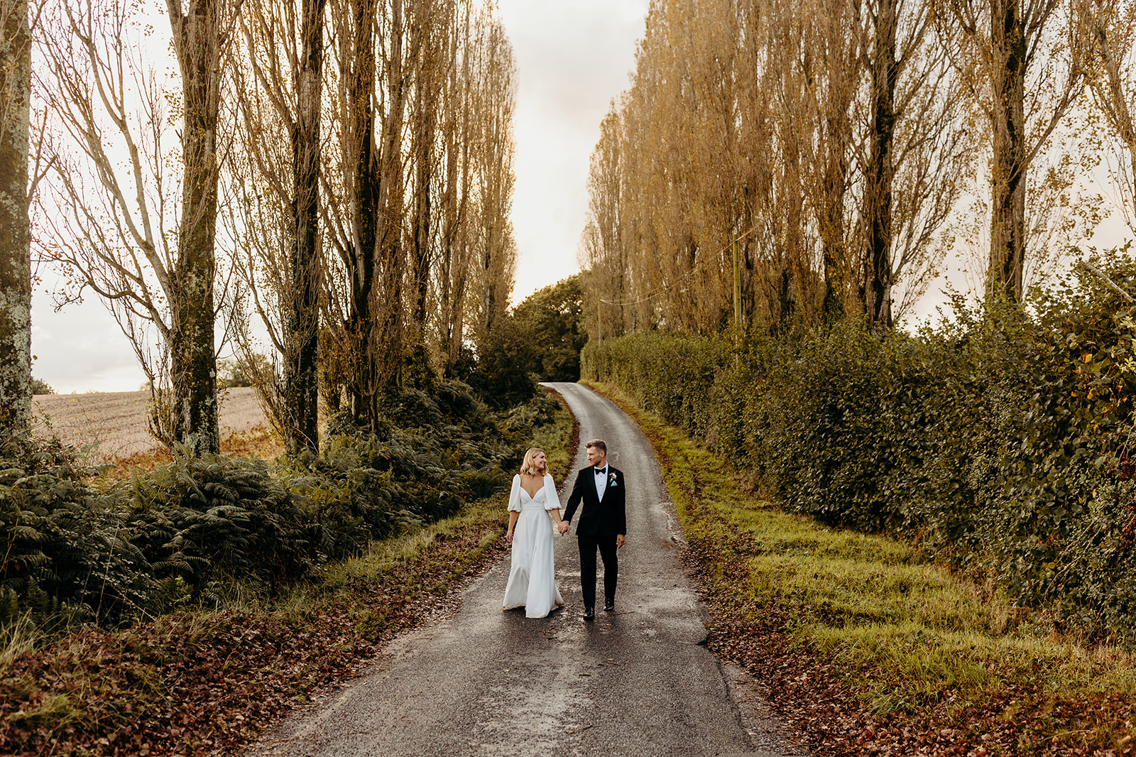 Couple pose for photographs surrounded by rows of trees at Silchester farm wedding