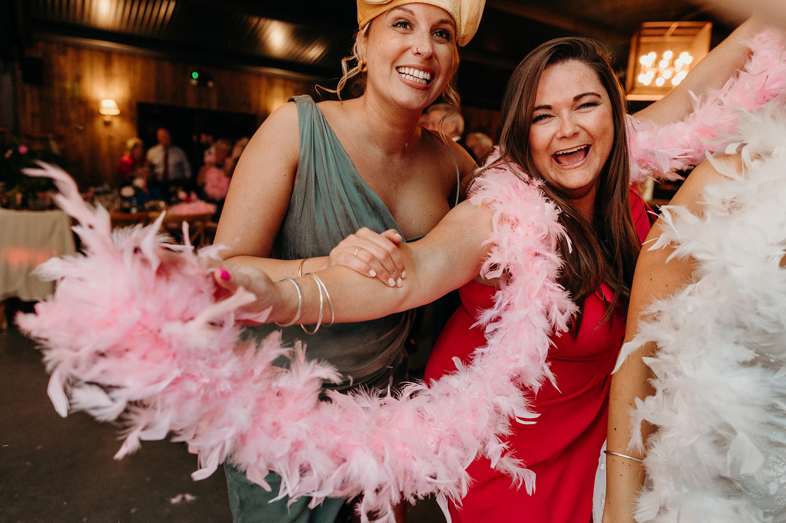 Wedding guests donning fun feathers, hats, and costumes as the barn wedding party reaches its peak.
