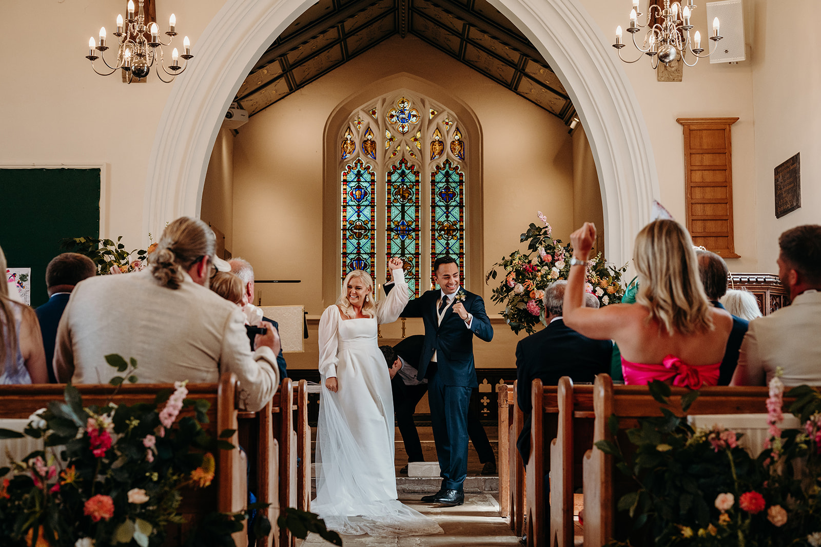 bride and groom hands in air after just getting married at church weddding