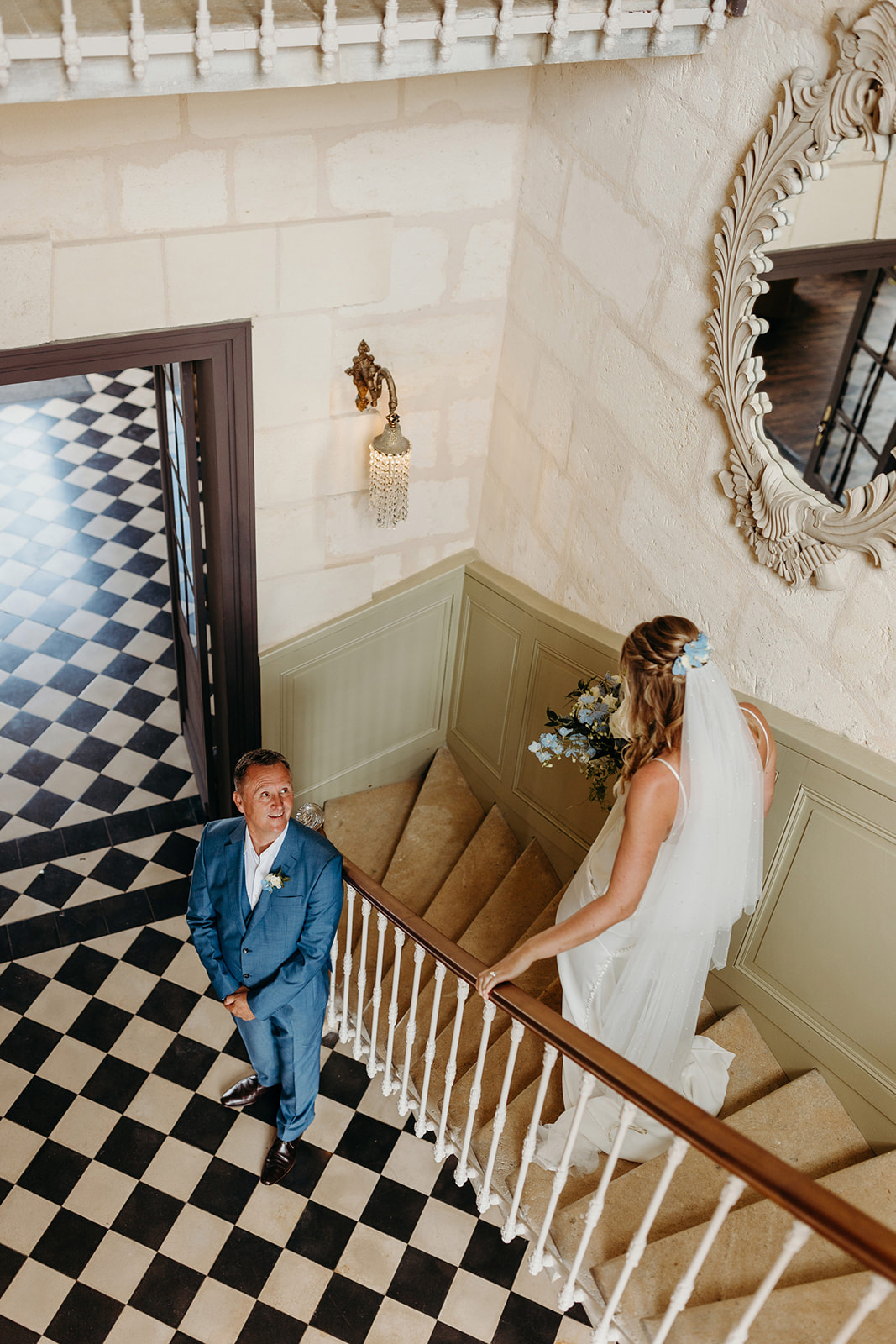 father of bride waiting at bottom of steps as bride walks down steps at Chateau wedding