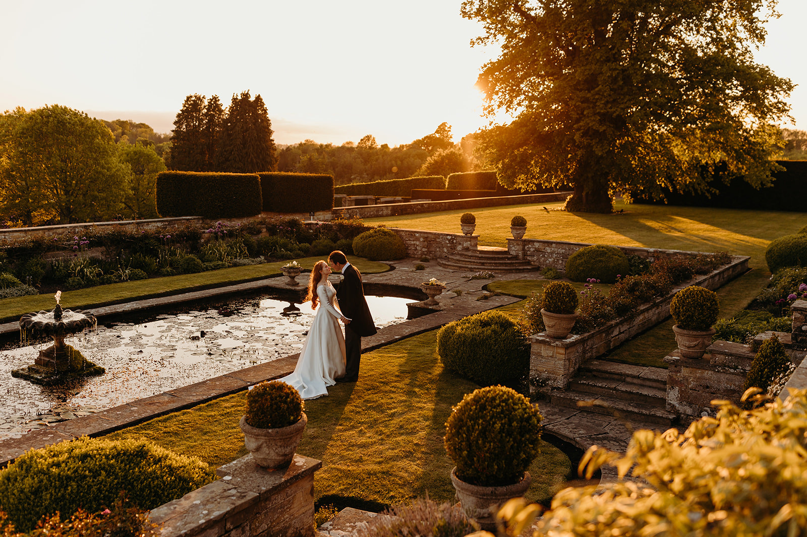 Bride and groom pose for photographs at sunset in Buckhurst Park gardens