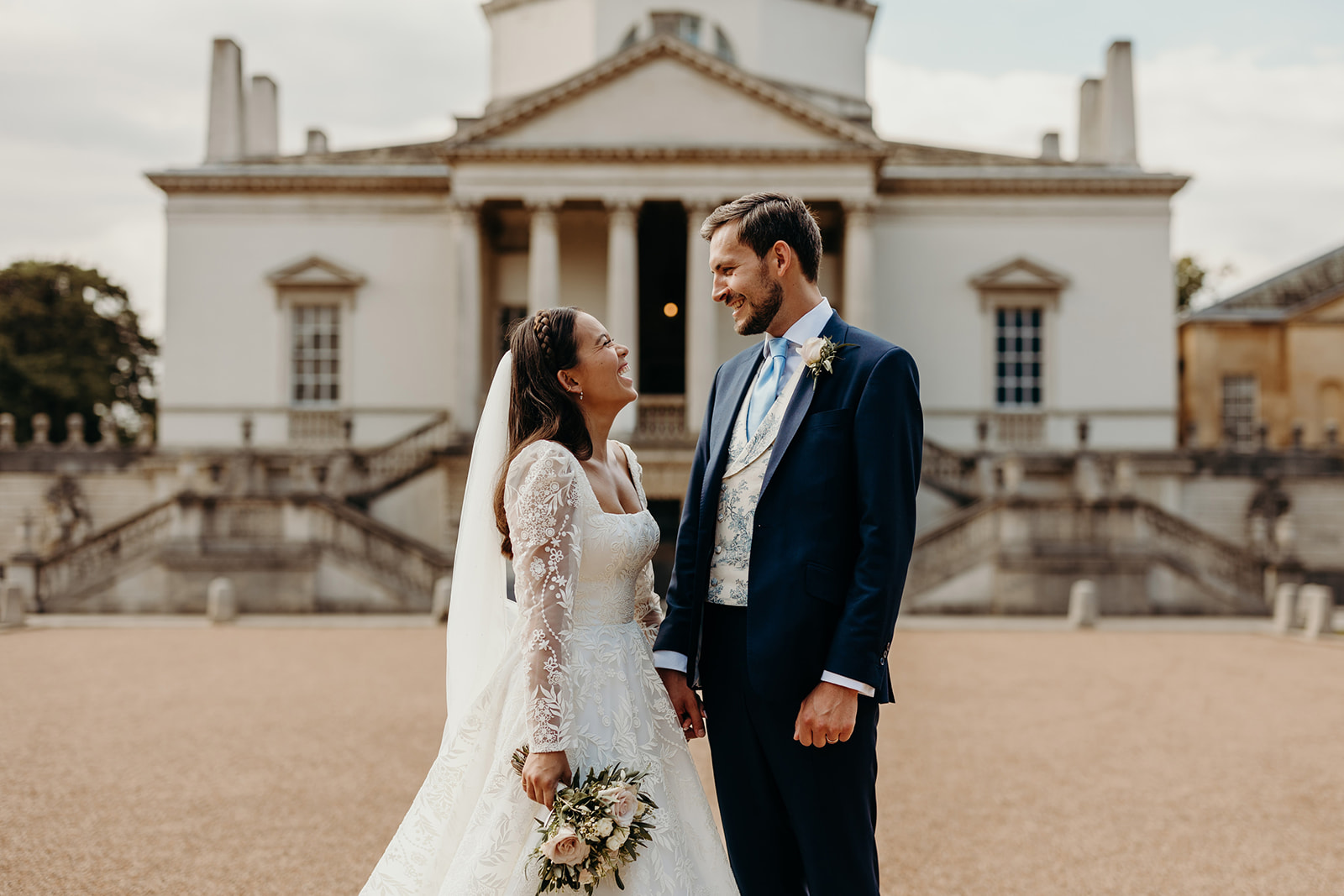 bride and groom look at each other with Chiswick house in background 