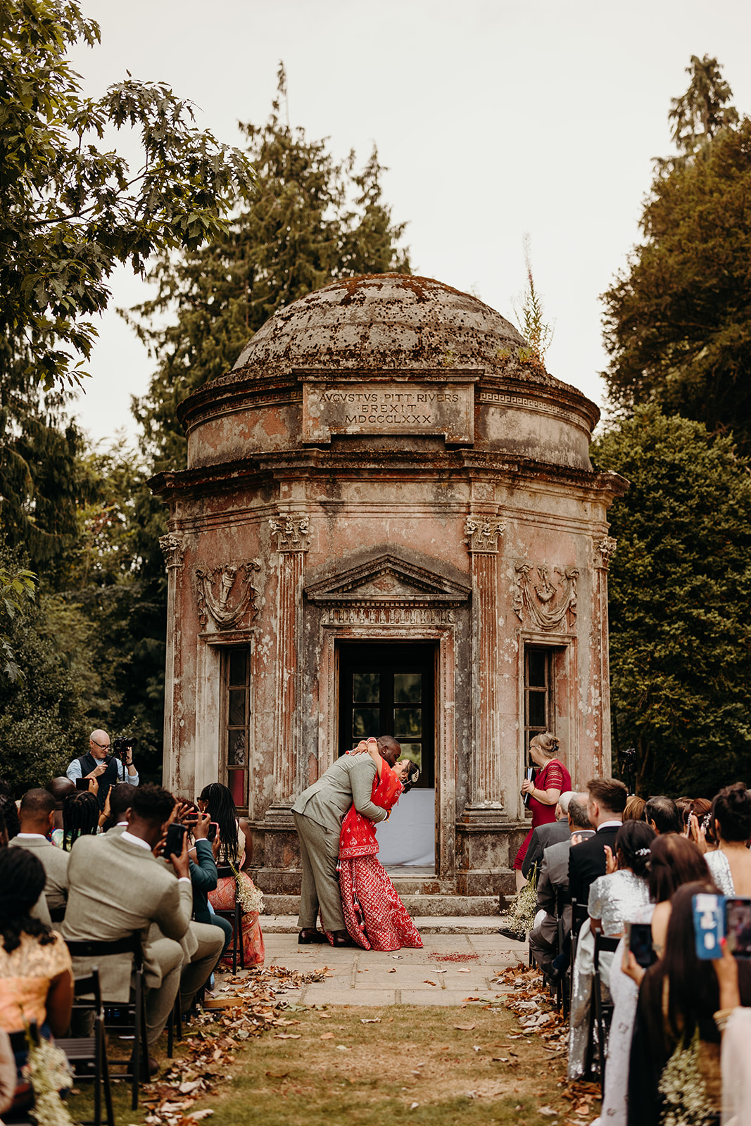 bride and groom kiss at Larmer Tree Gardens roman temple wedding ceremony