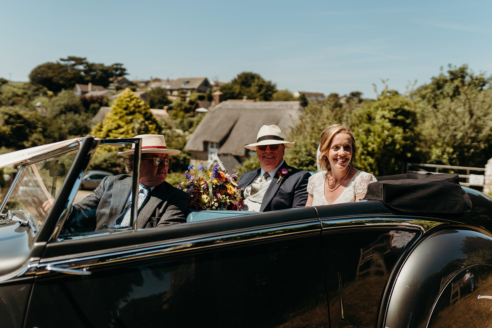 bride arrives with father in open vintage car at Dorset wedding