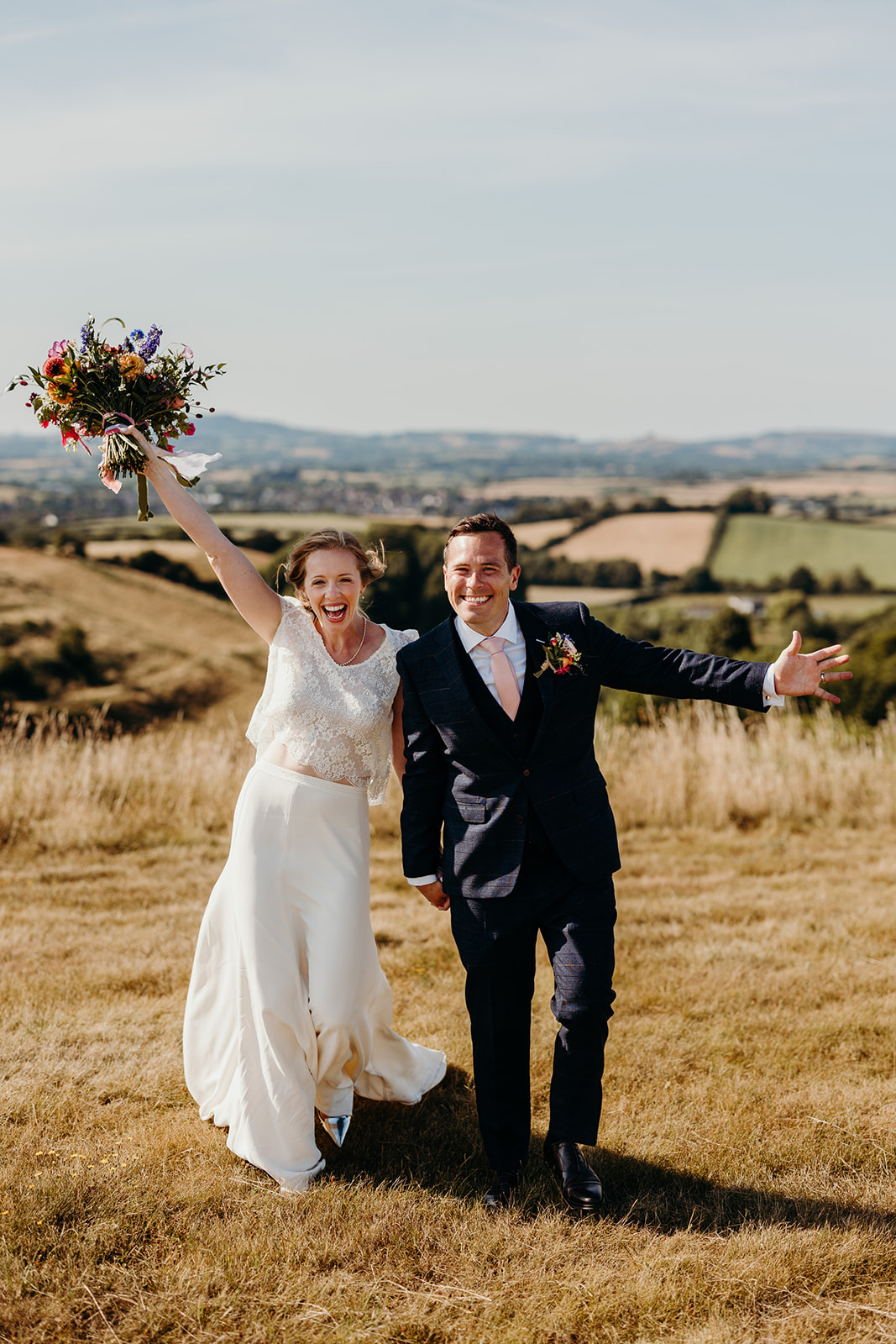 Bride and groom pose for photographs with Dorset rolling hills in the background