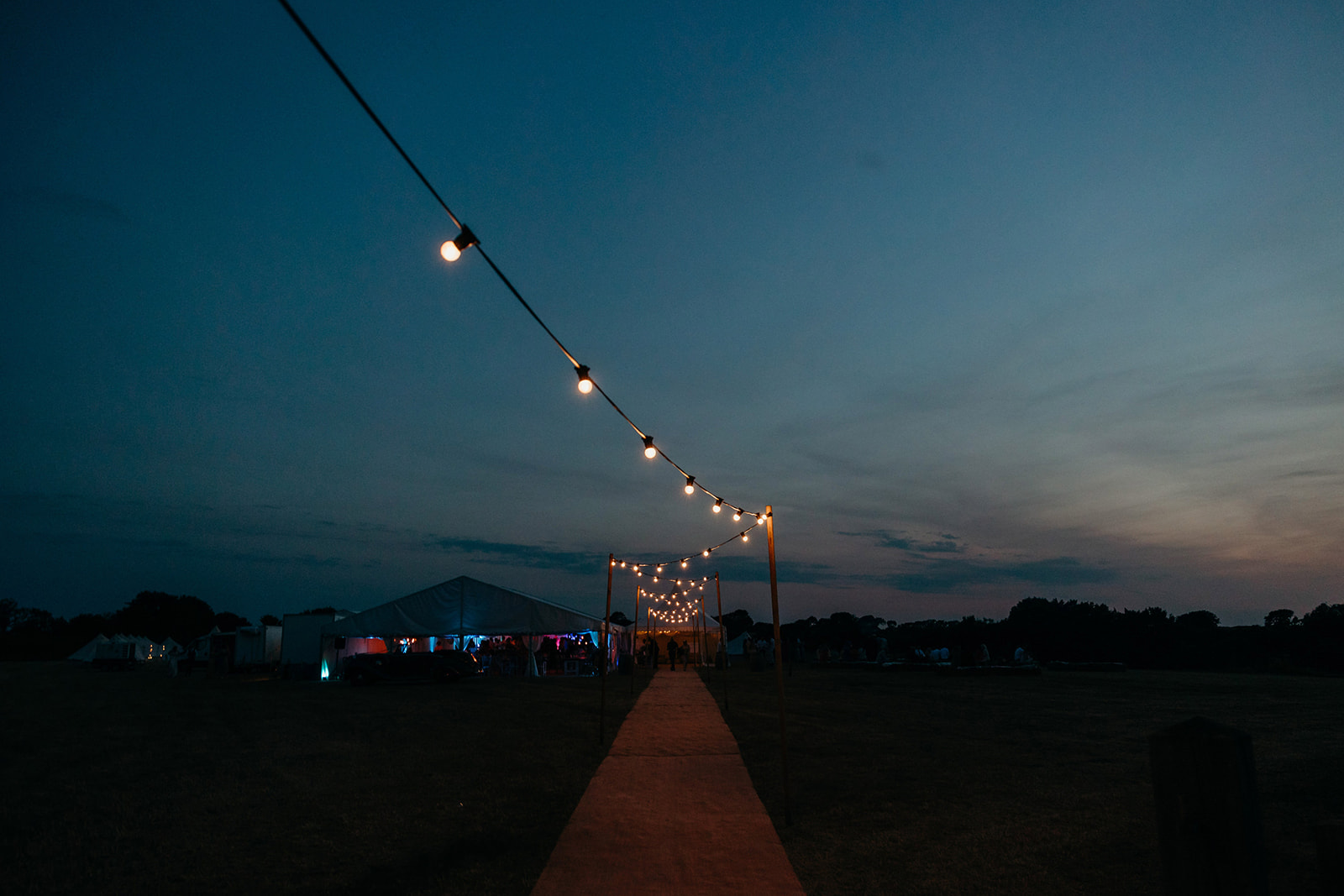sunsets at Marquee wedding festoon lighting lights the way to the marquee