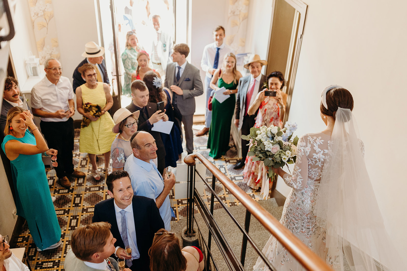 Guests watching bride come down stairs 
