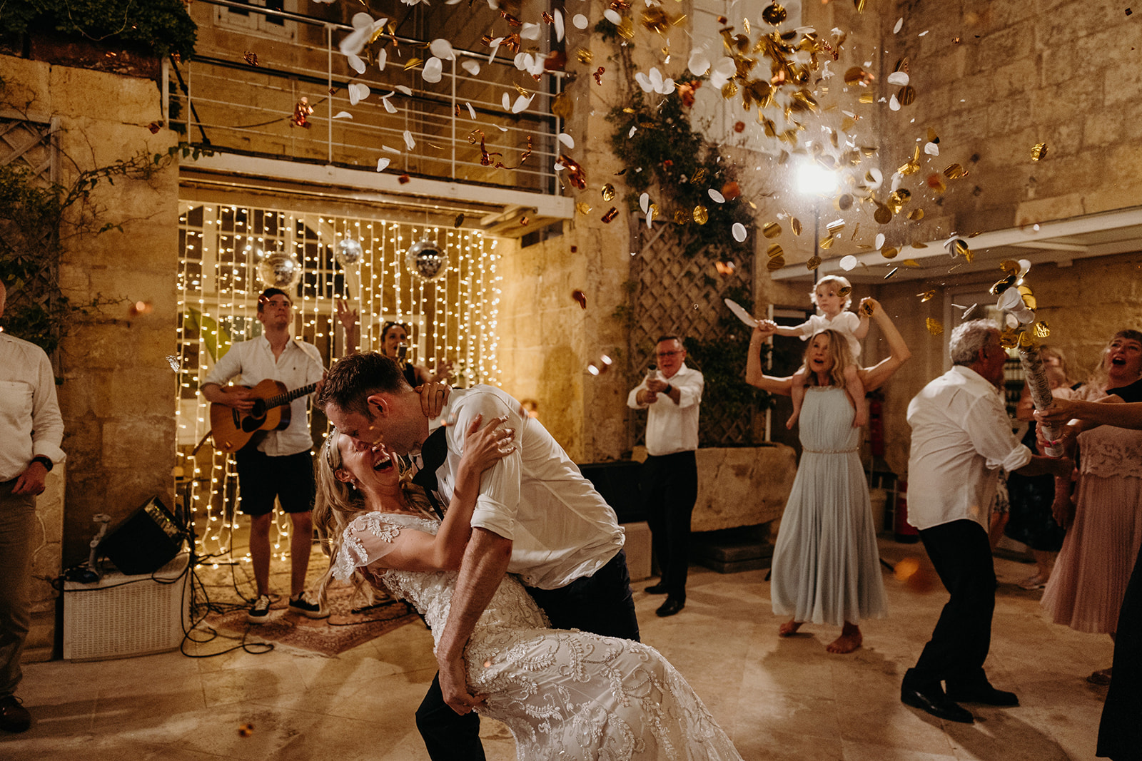 Confetti being throw in air as groom dances with bride
