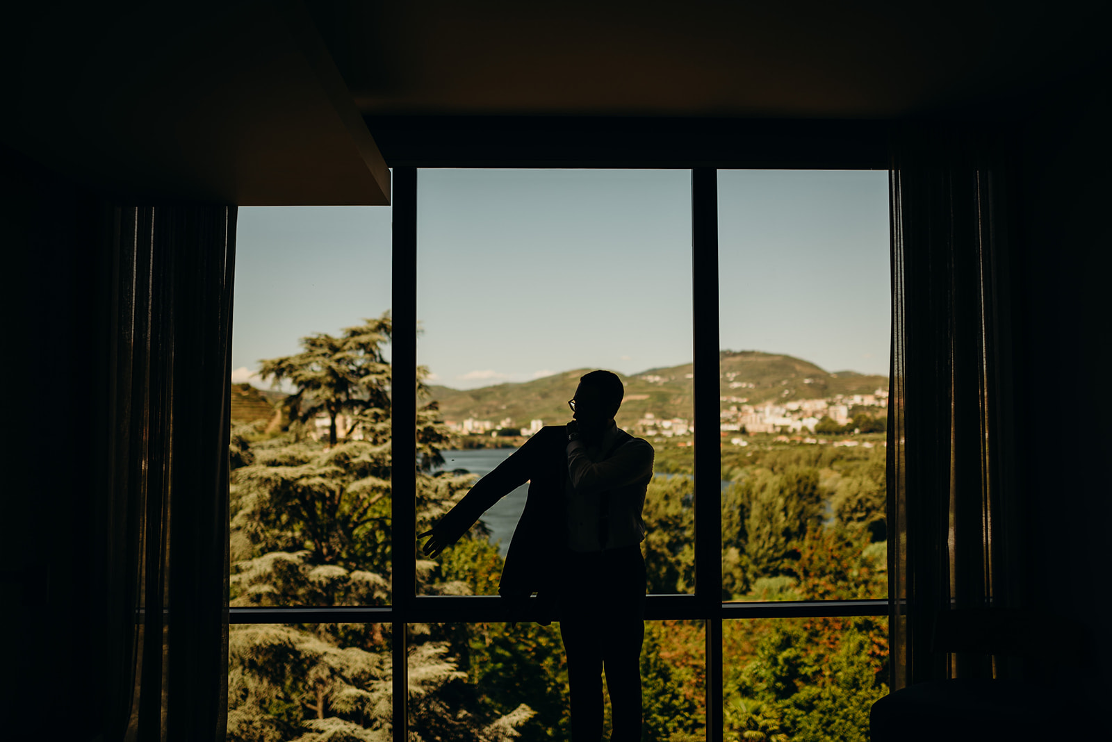 Groom gets ready silhouetted by window