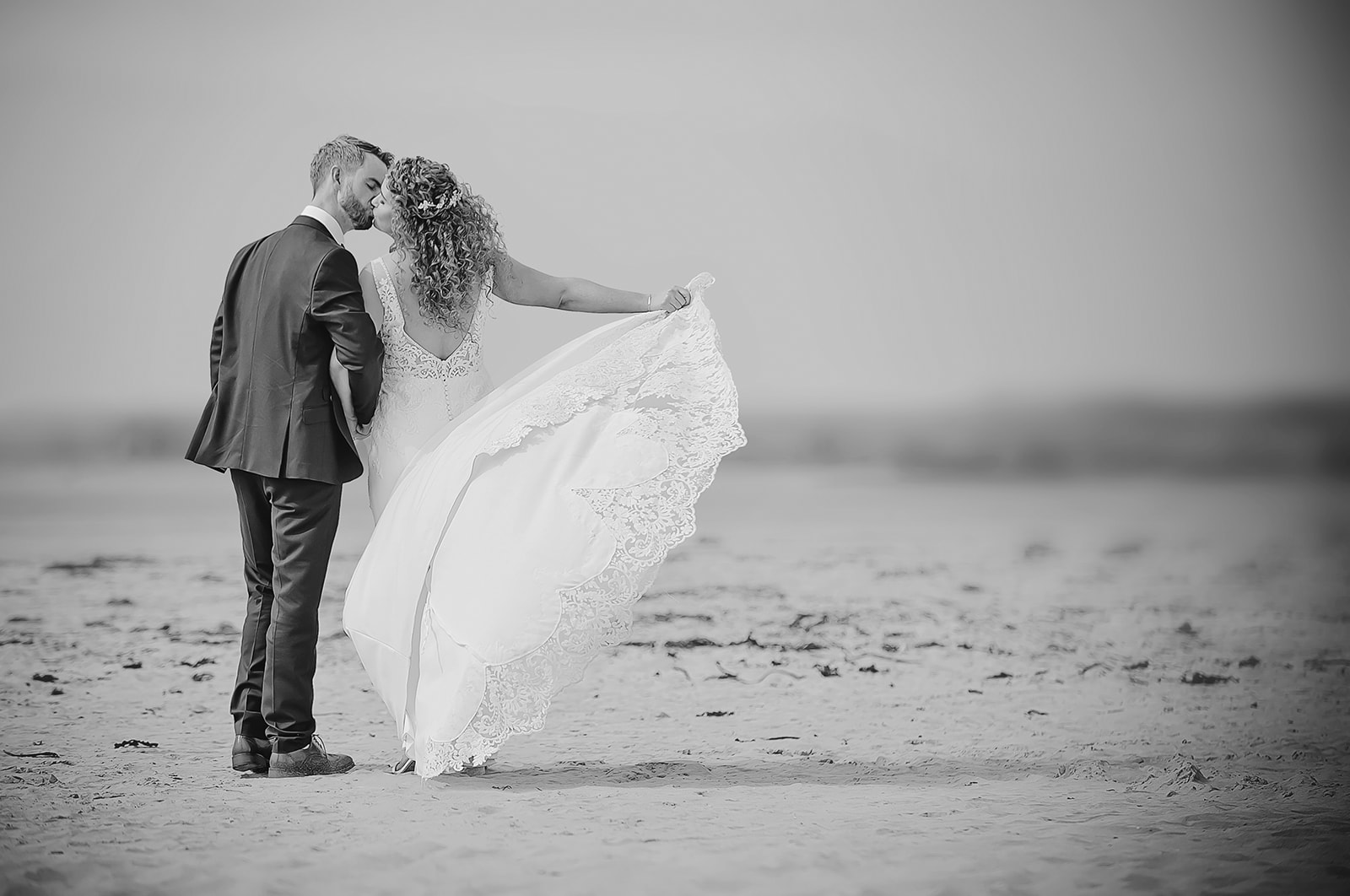 Black and white photo of a couples strolling along the beach in Ennis scone Sligo before their wedding at the Ocean Sand