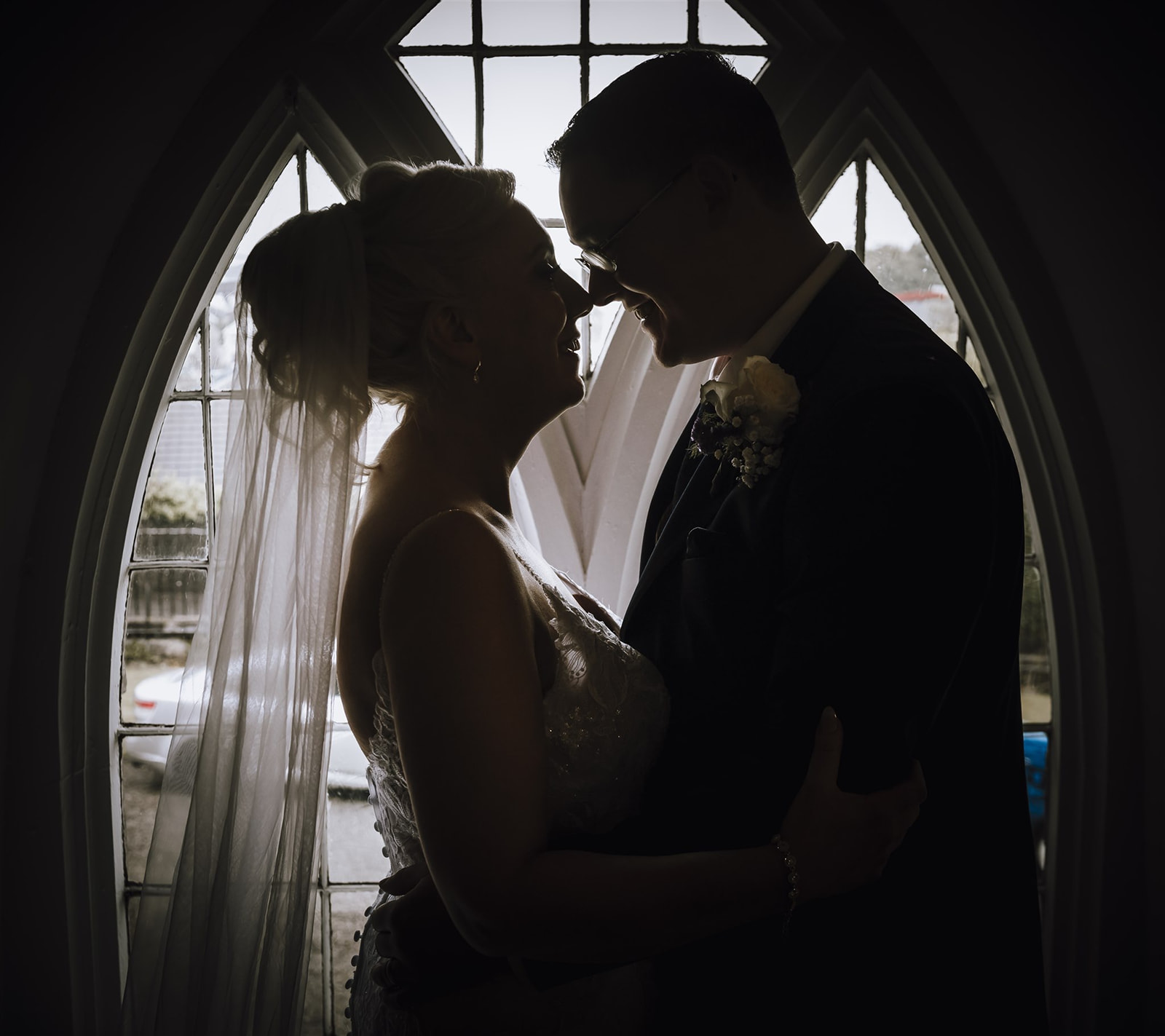 Silouette of the bride and groom embracing at a window in the church in Ballina