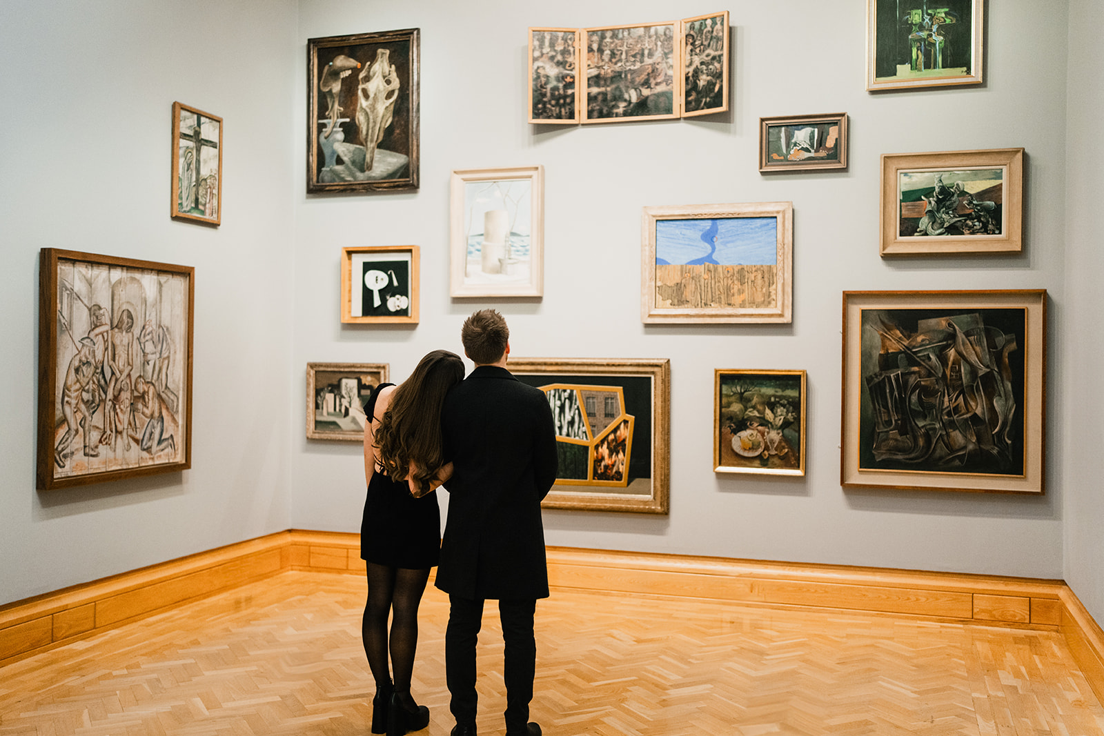 couple hugging each other amongst art work in an art gallery