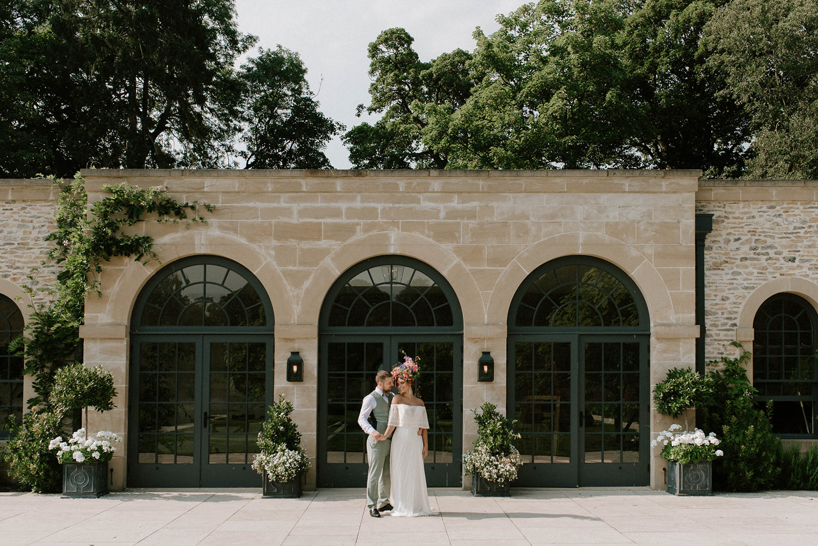 bride and groom standing outside arched windows of fig house at Middleton lodge