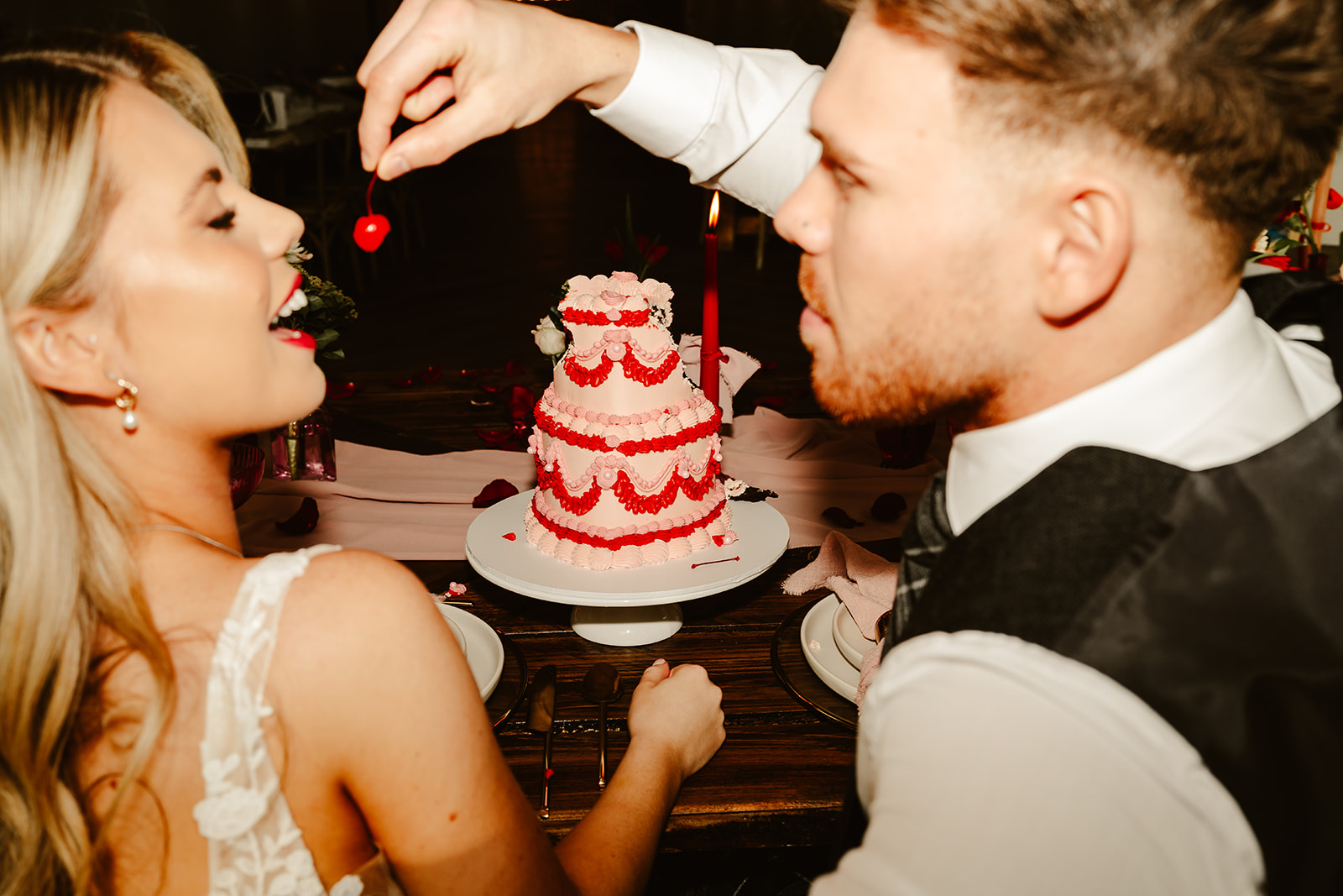 bride and groom sit at dinner table eating wedding cake 