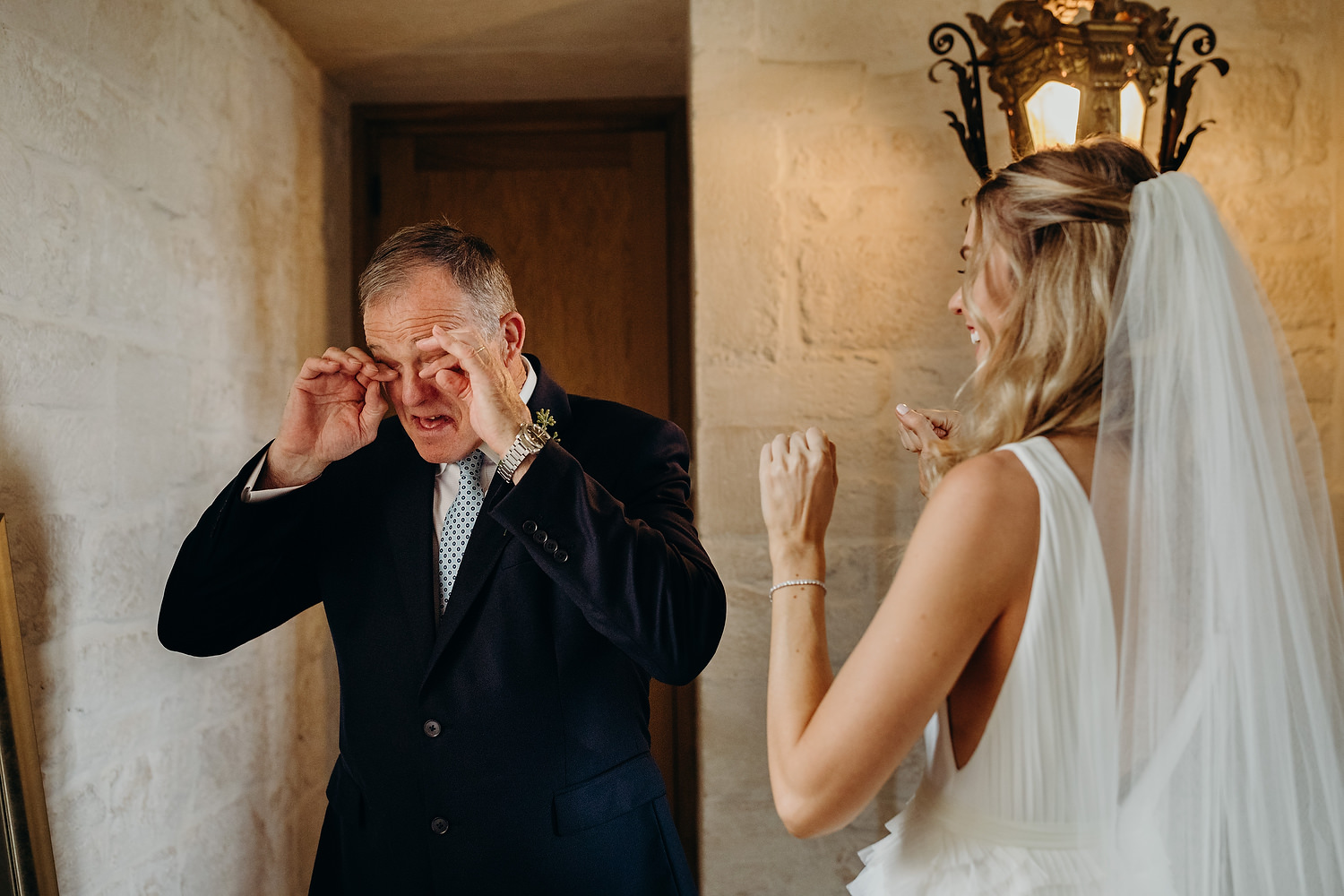 father of bride wiping tear as he see daughter in wedding dress