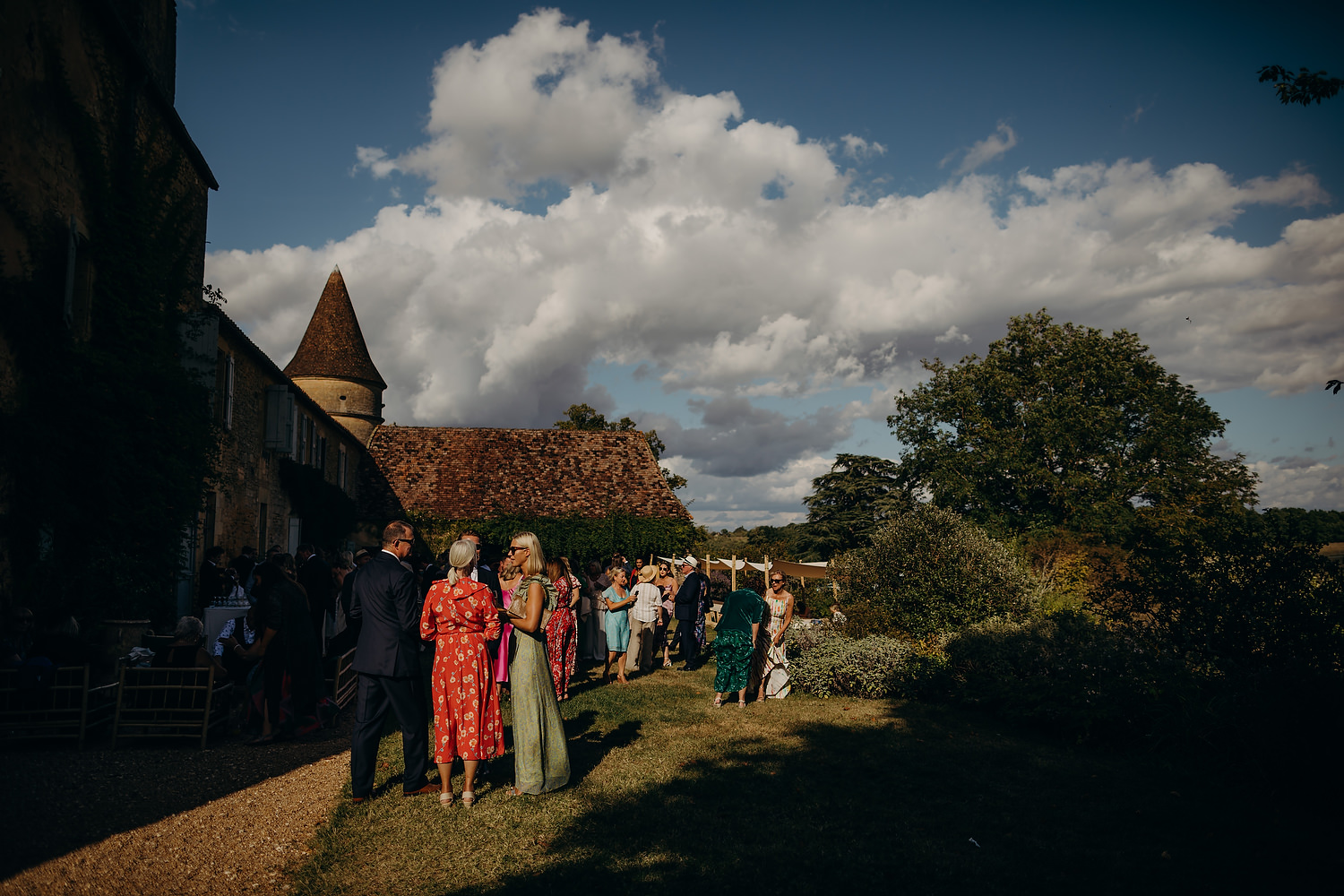 guests mingle at chateau wedding in the Dordogne with thick clouds in the background