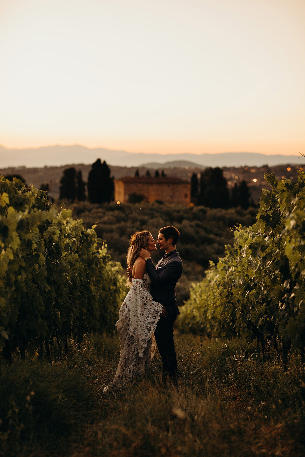 Bride and groom pose for photographs down tuscany vineyard wedding