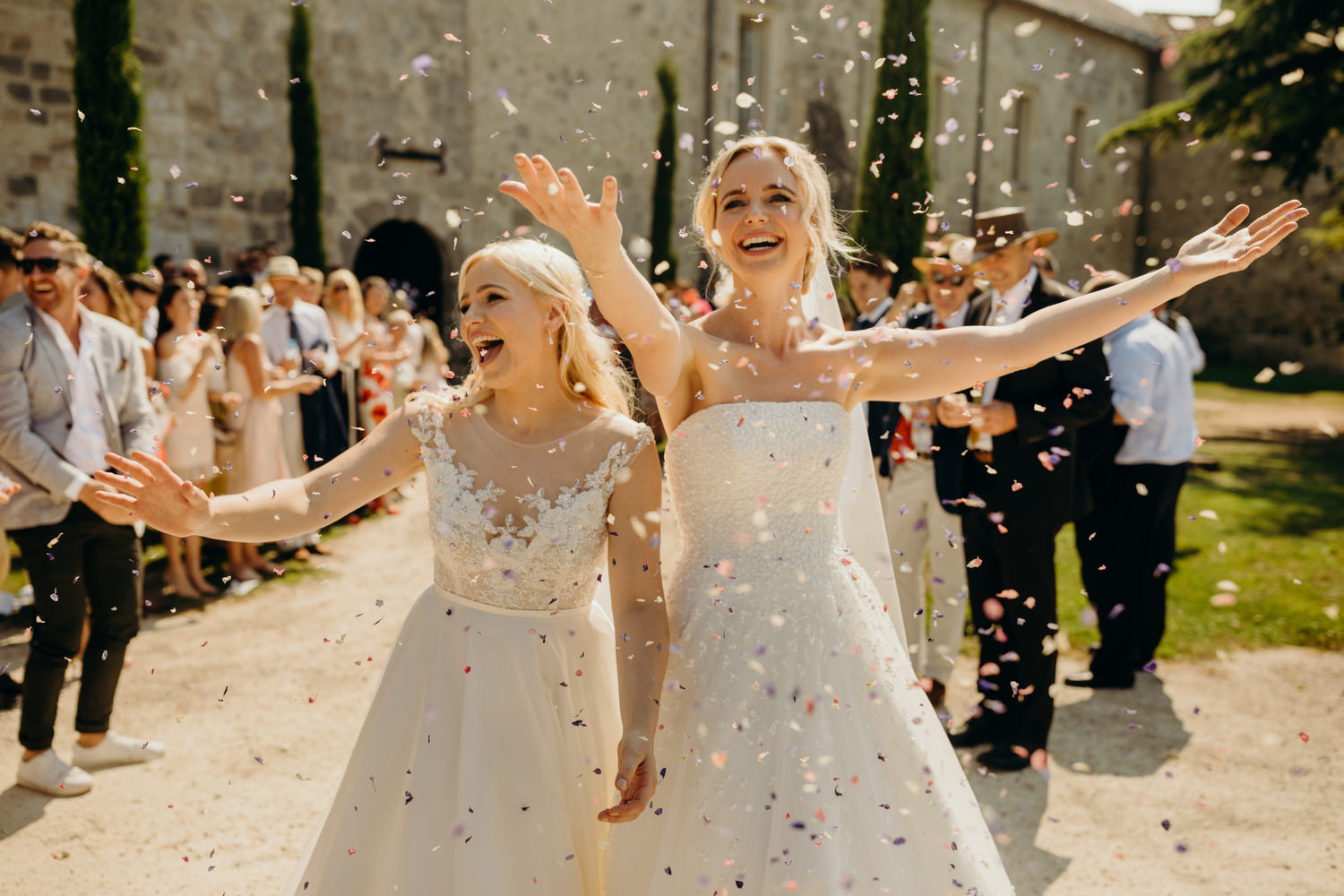 brides getting covered with confetti at wedding in france