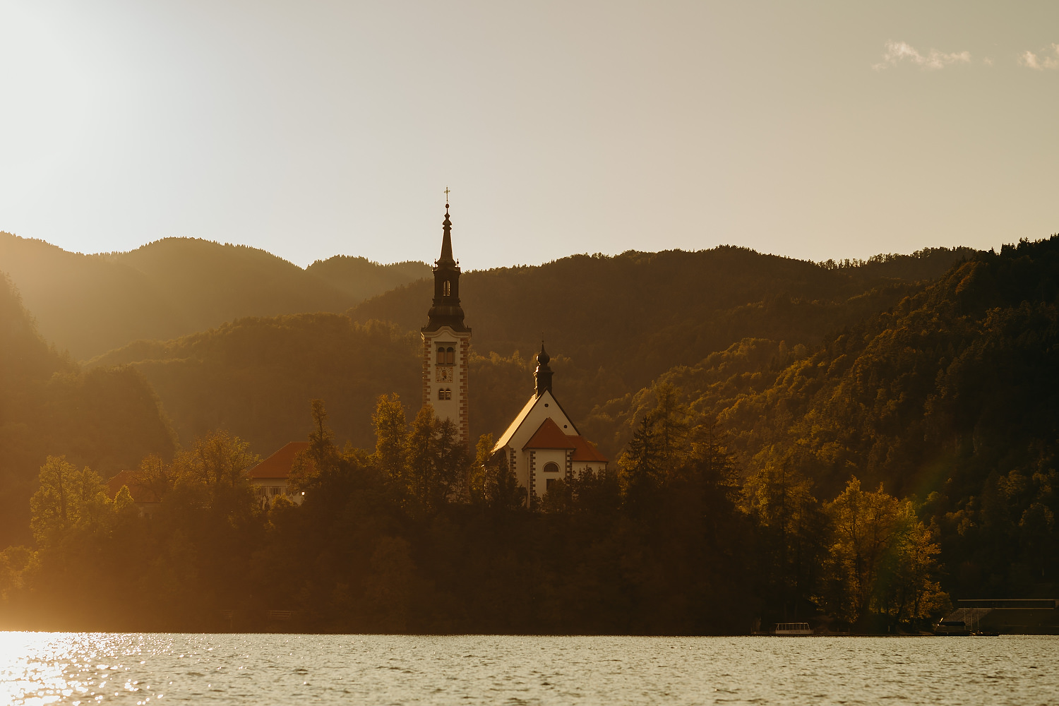 church in middle of lake bled at sunset