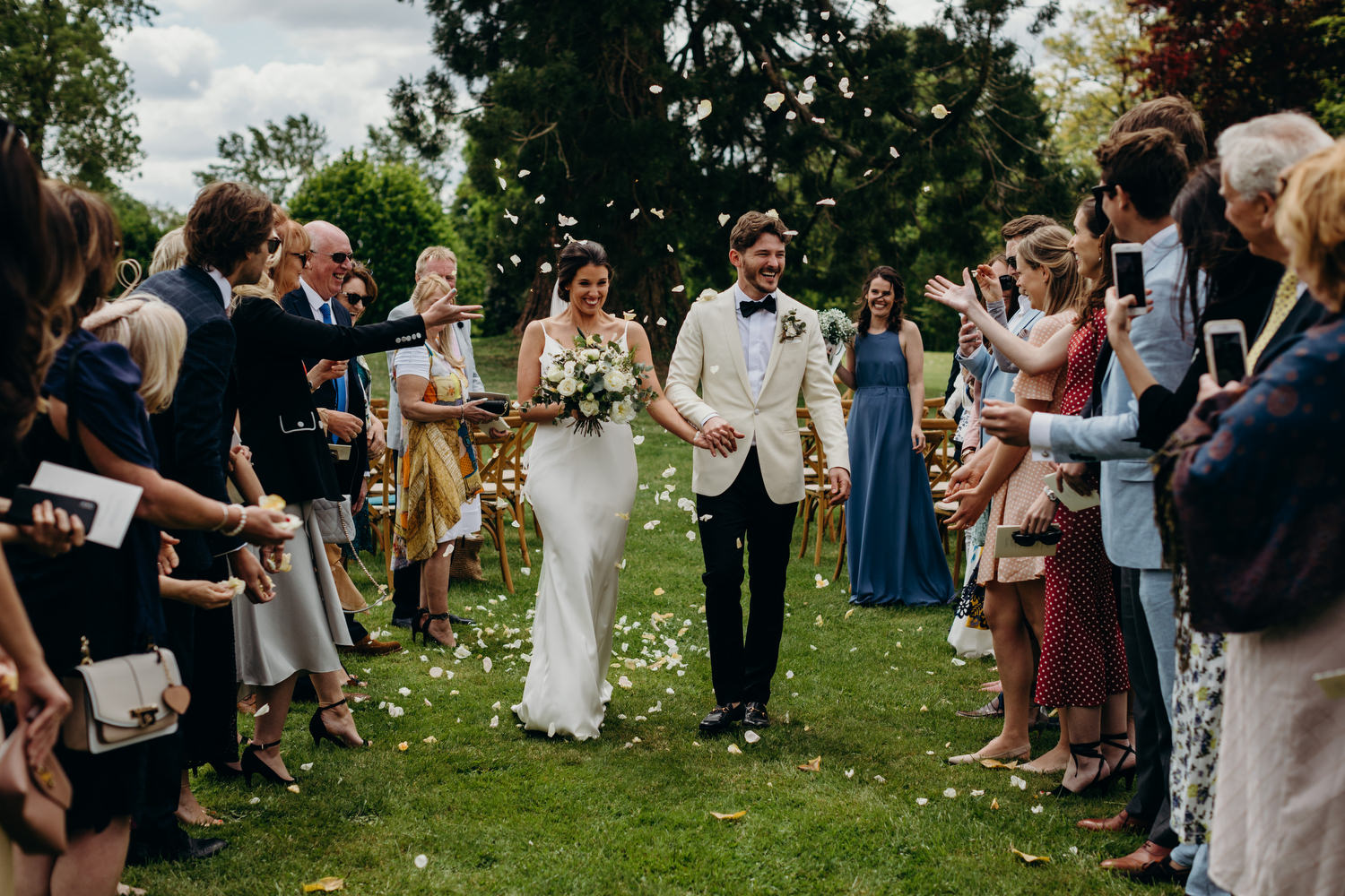 bride and groom get showered with confetti in outdoor ceremony