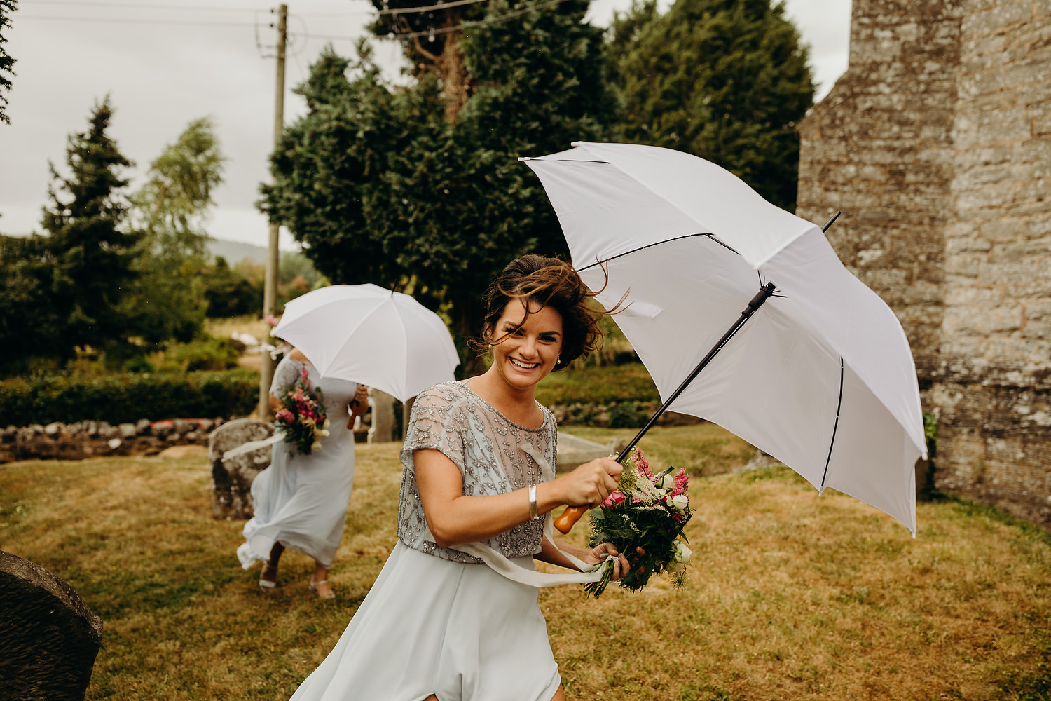 bridesmaid running with umbrella at rainy wdding