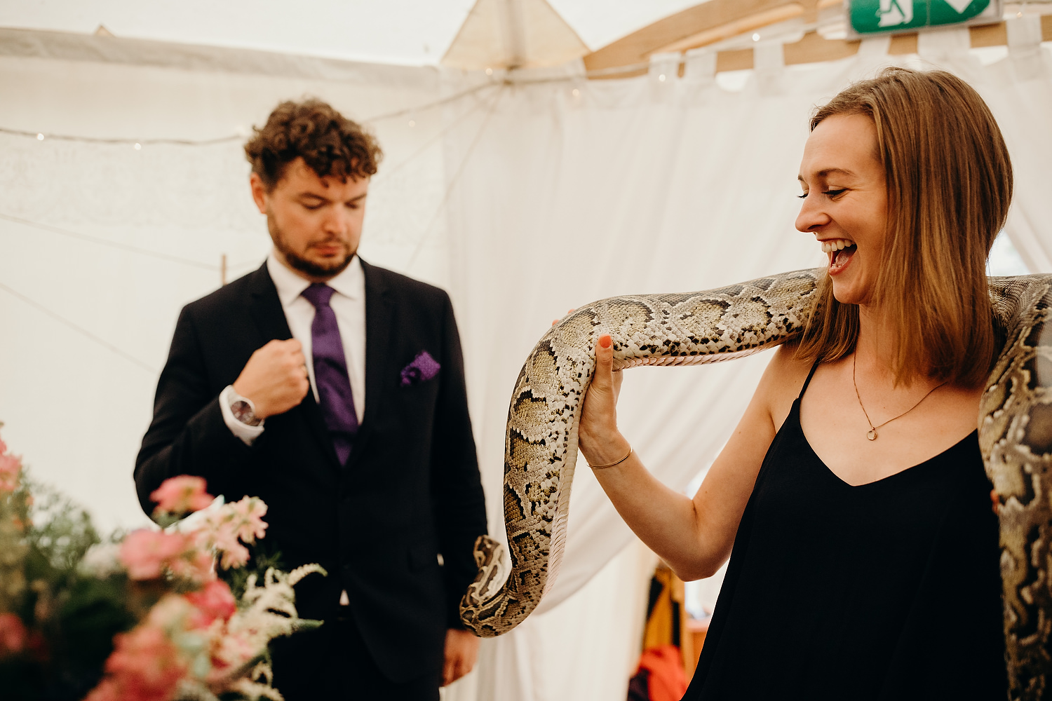 man looks scared as woman holds snake at wedding