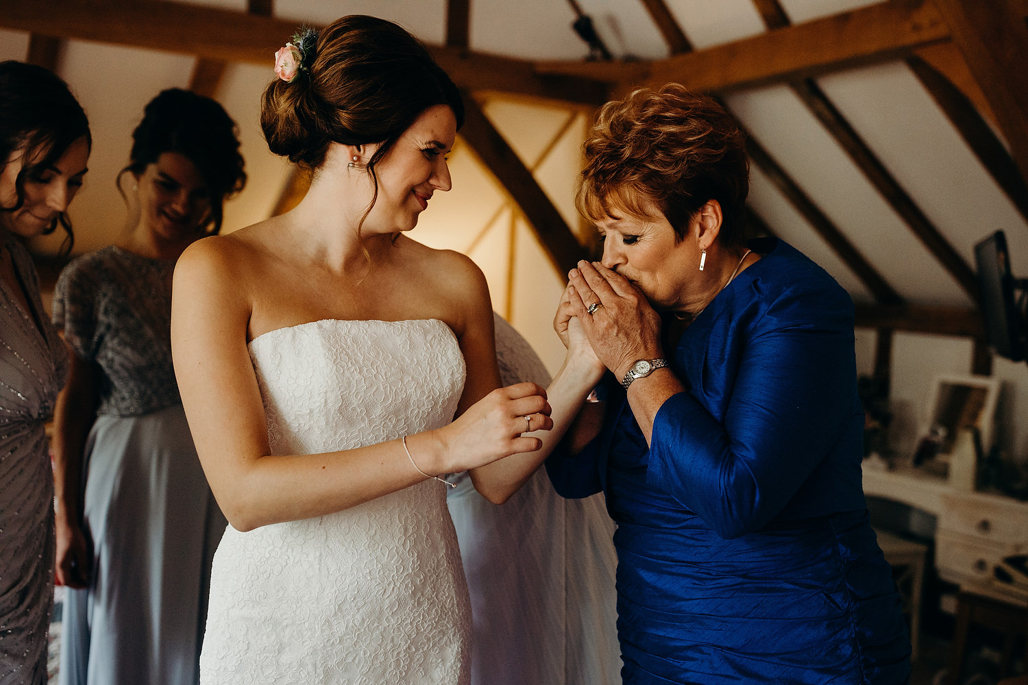 mother of bride kisses daughters hand as she gets ready for wedding