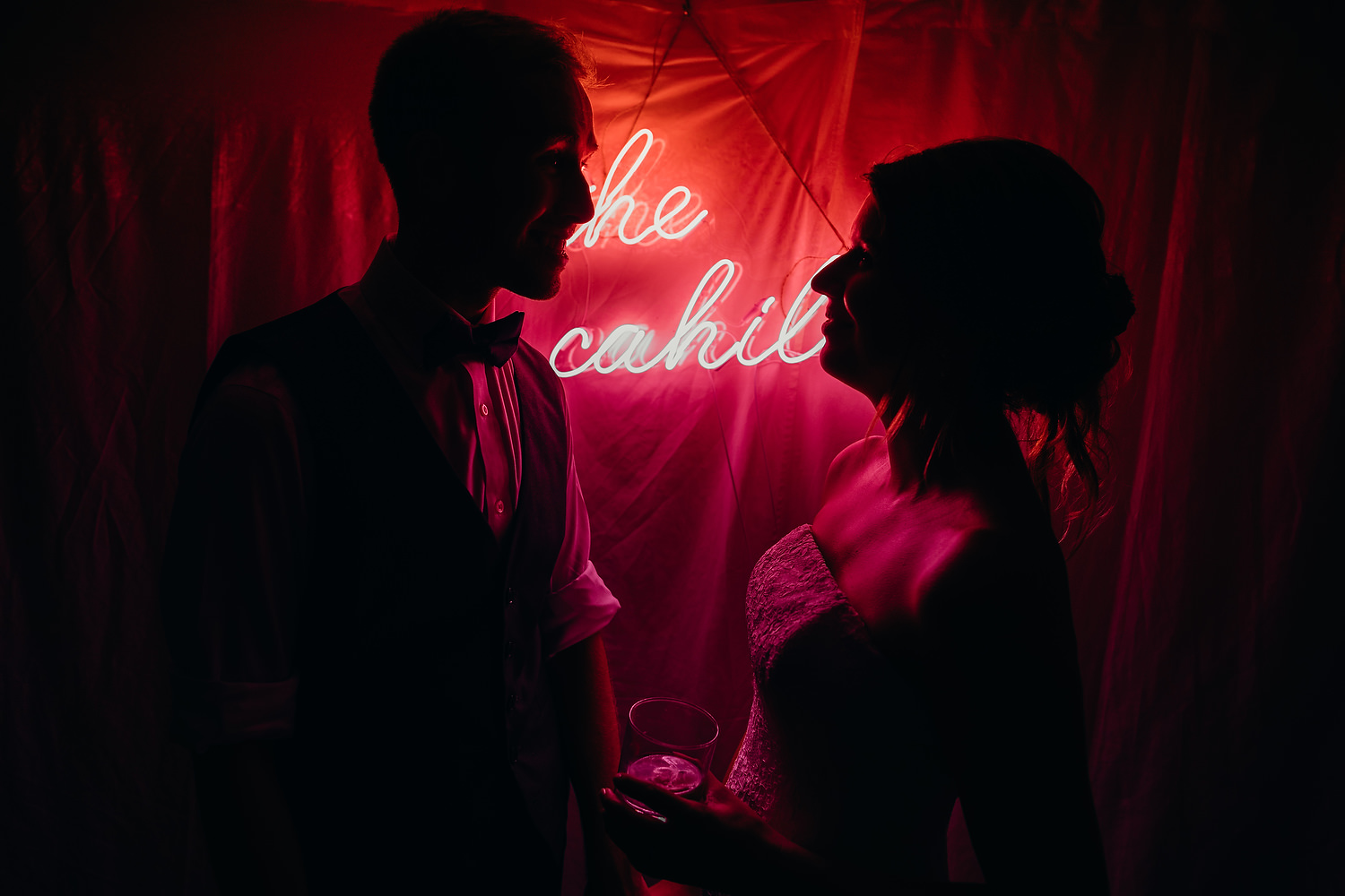 silhouetted bride and groom with their surname lit up in neon behind them