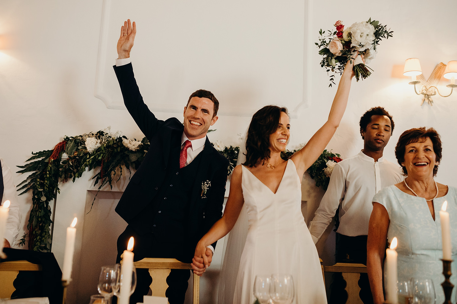 bride and groom waving hands in air as the make an entrance to their wedding dinner