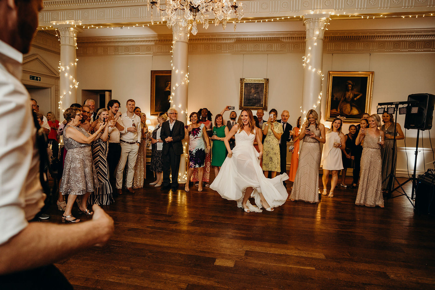 bride and groom first dance with guests all watching behind