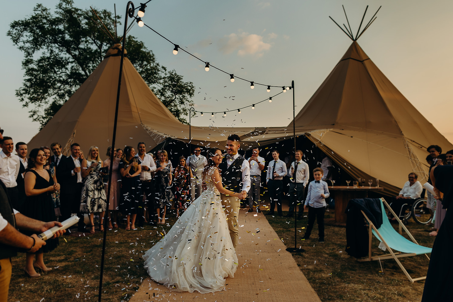 bride and groom first dance outside tipi at sunset with guests watching
