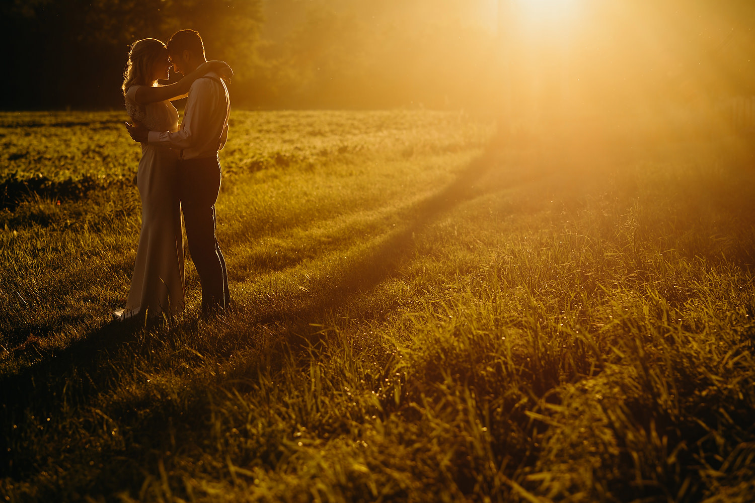 Bride and groom at sunset with orange flare from sun