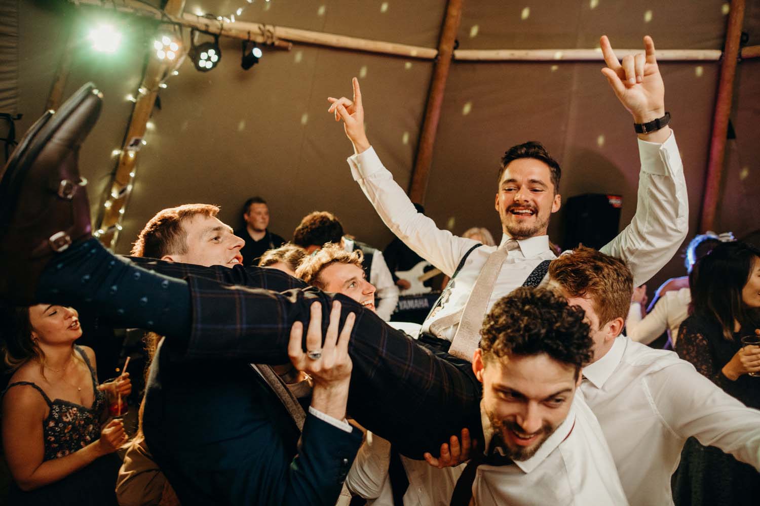 groom being lifted up in air during wedding party