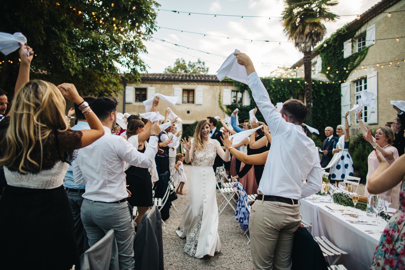 Bride dancing down the tables as guests wave their napkins in the air