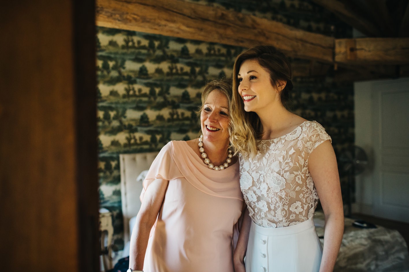 Brides mum hugging daughter as she gets into her wedding dress