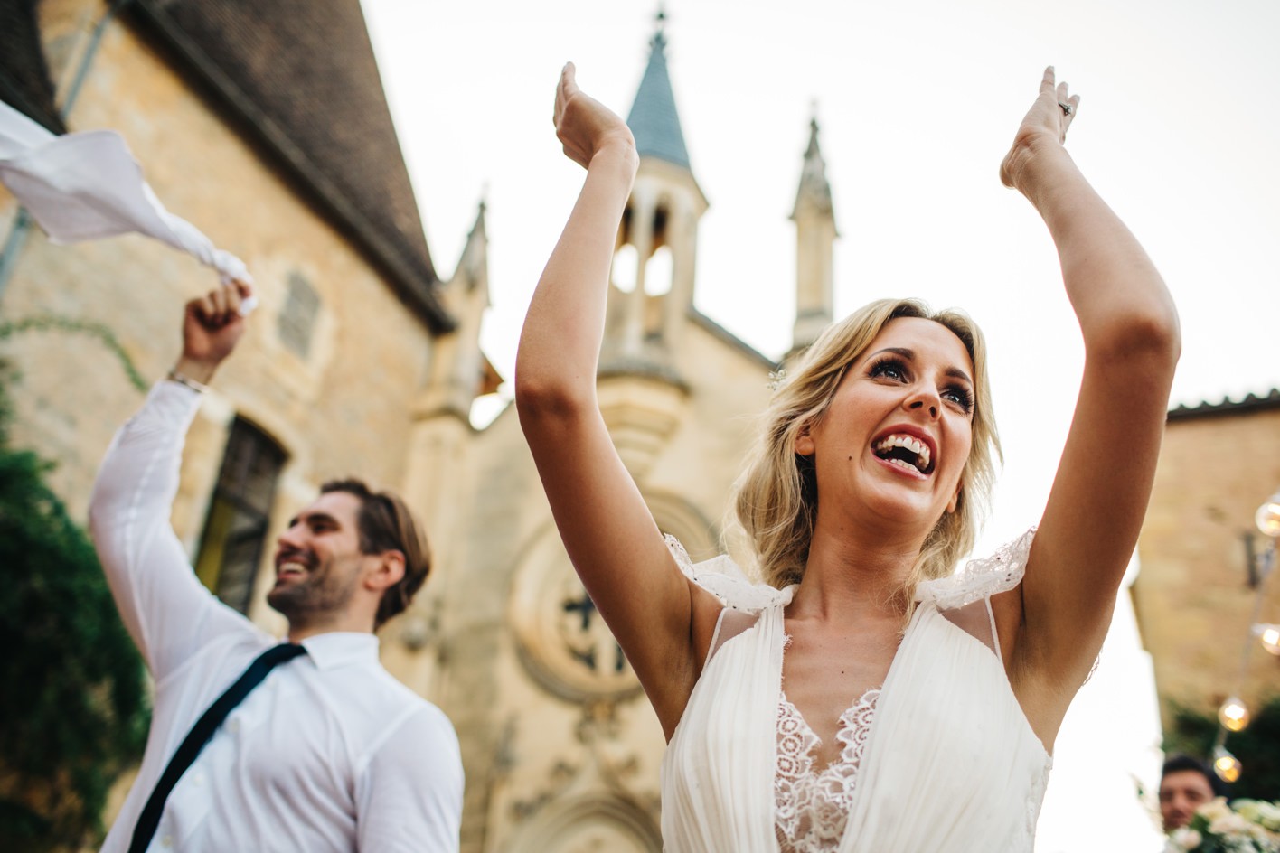 bride and groom waves hands in air as singing waiters surprise everyone