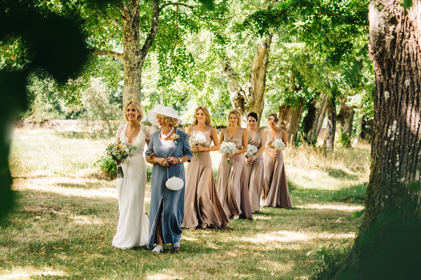 Bride leading walk with bridesmaids at wooden ceremony in France