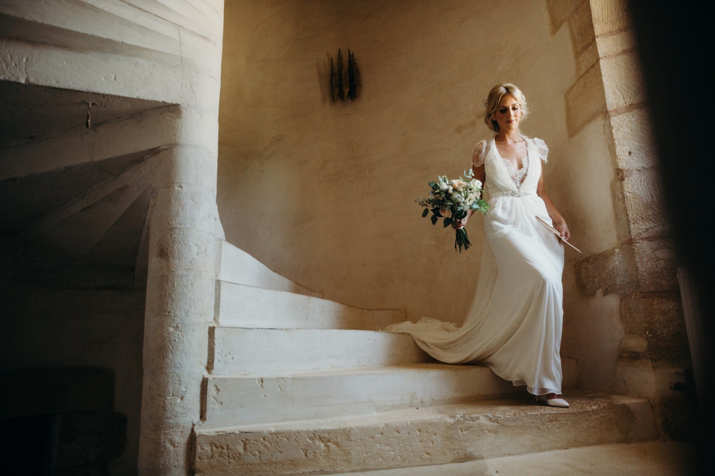 bride walking down stone stairs at Chateau de la Bourlie