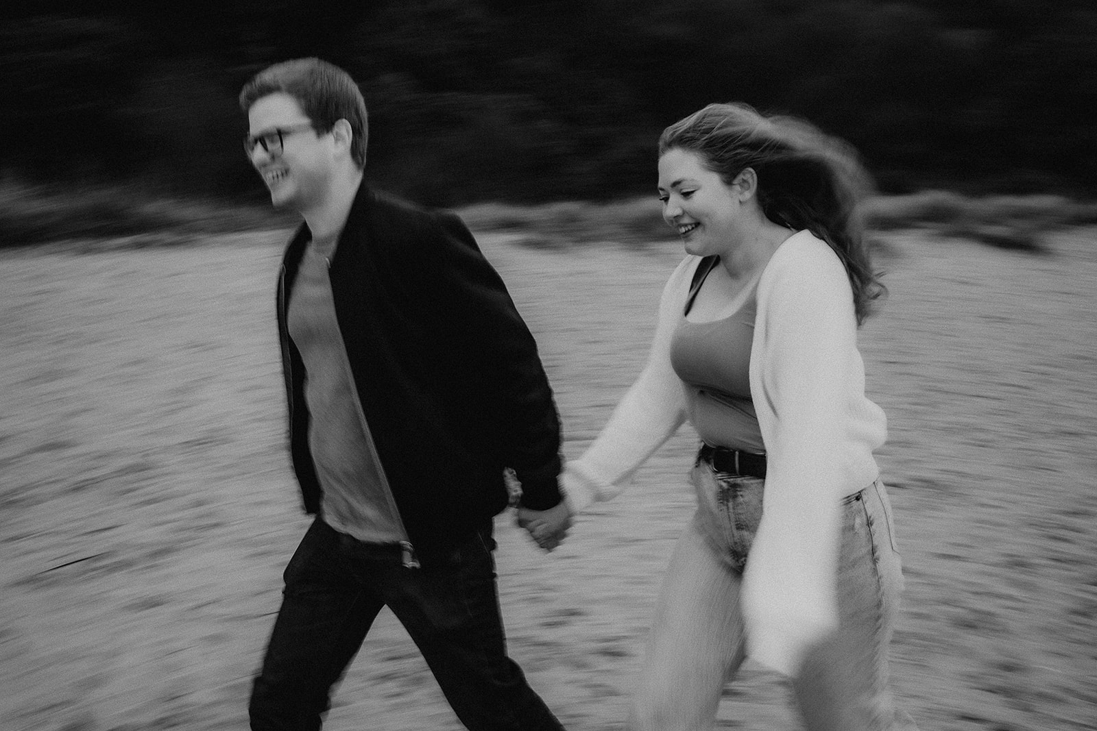 Motion blur photo of a couple running hand in hand along Highcliffe Beach at their pre-wedding photoshoot