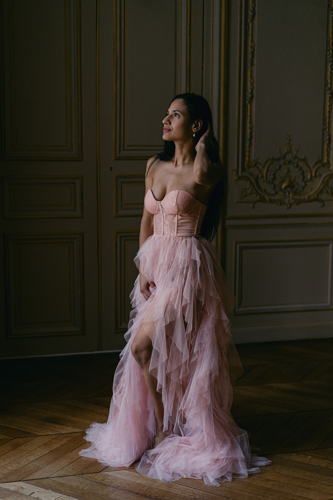 Woman in pink tulle dress illuminated by the window light in Paris hotel